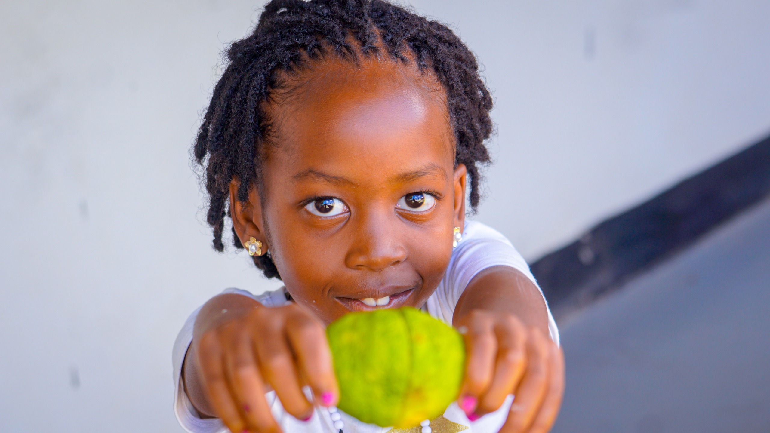 A child offering a piece of fresh fruit